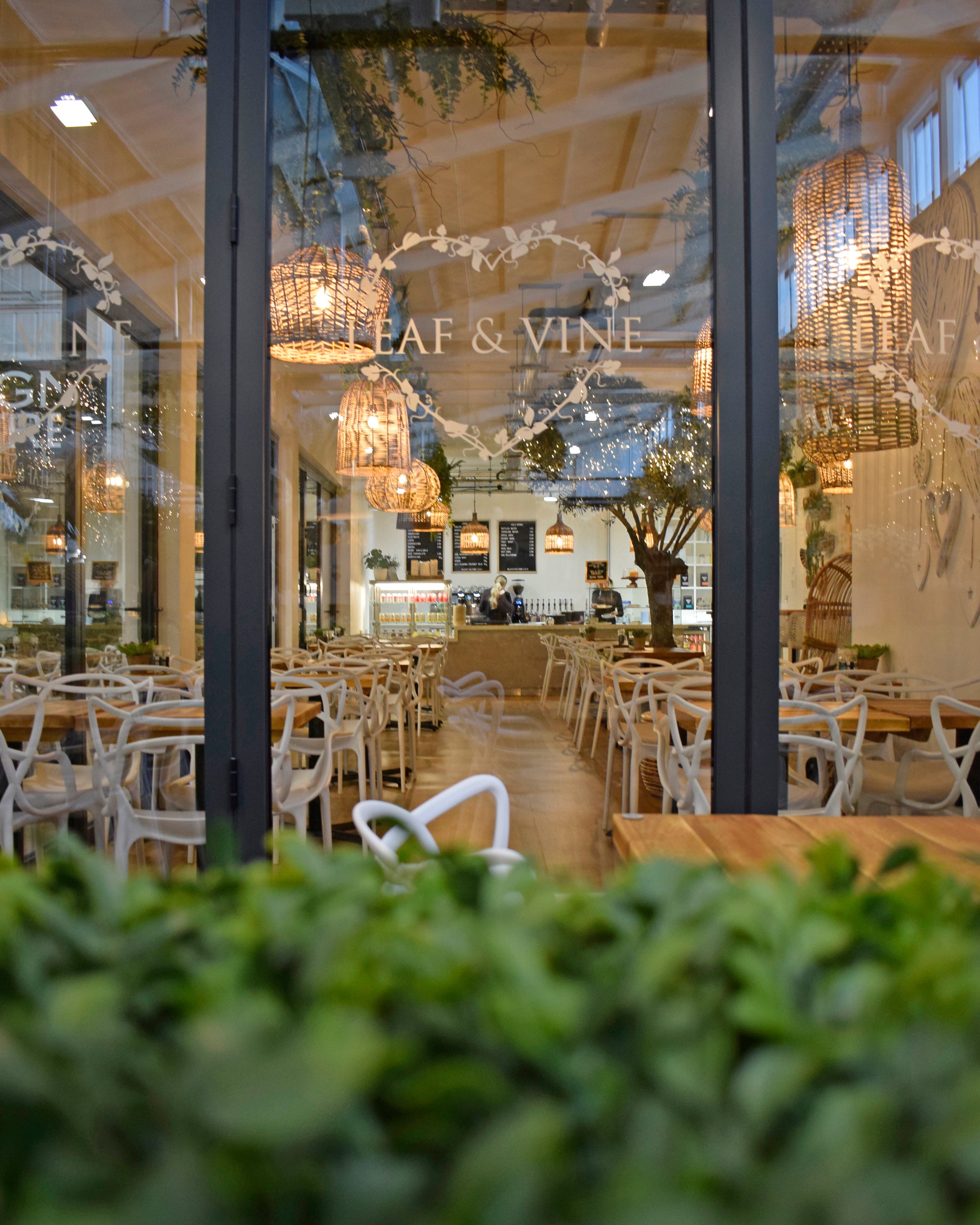 Exterior view of Leaf and Vine Coffee Shop with its stunning interior, lots of seating, and by-fold doors with a signs that read 'Leaf & Vine'